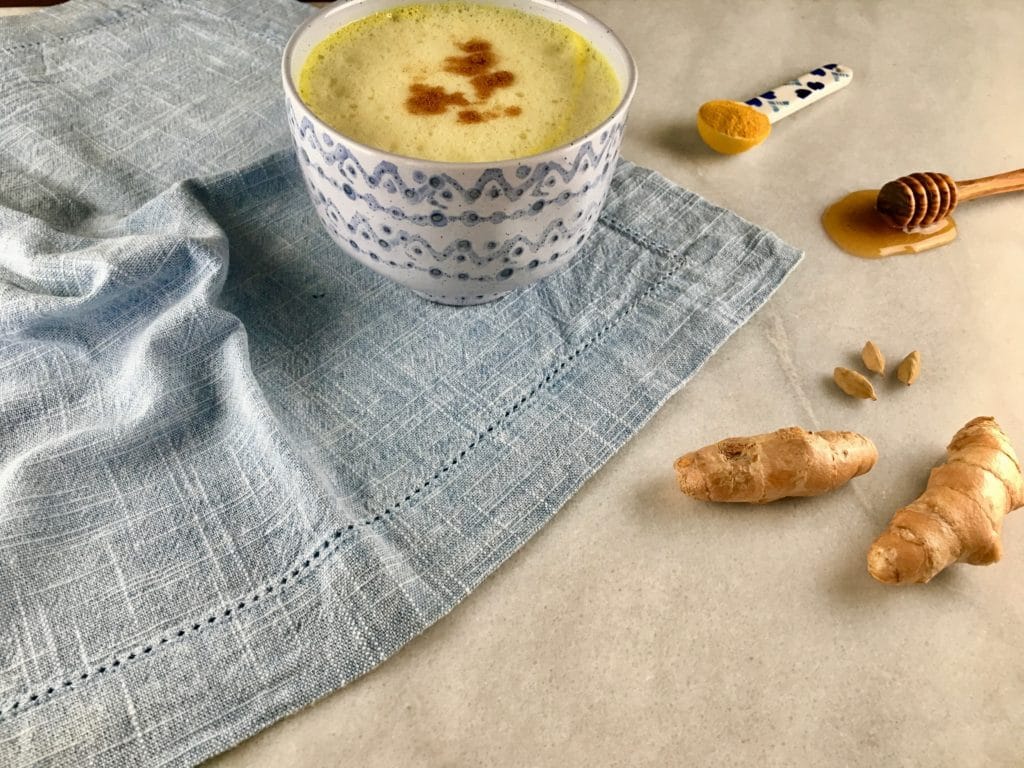 Turmeric latte with ginger, honey and ginger on spoons