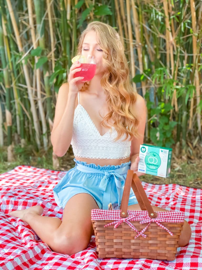 Woman drinking Superfood Tabs at picnic